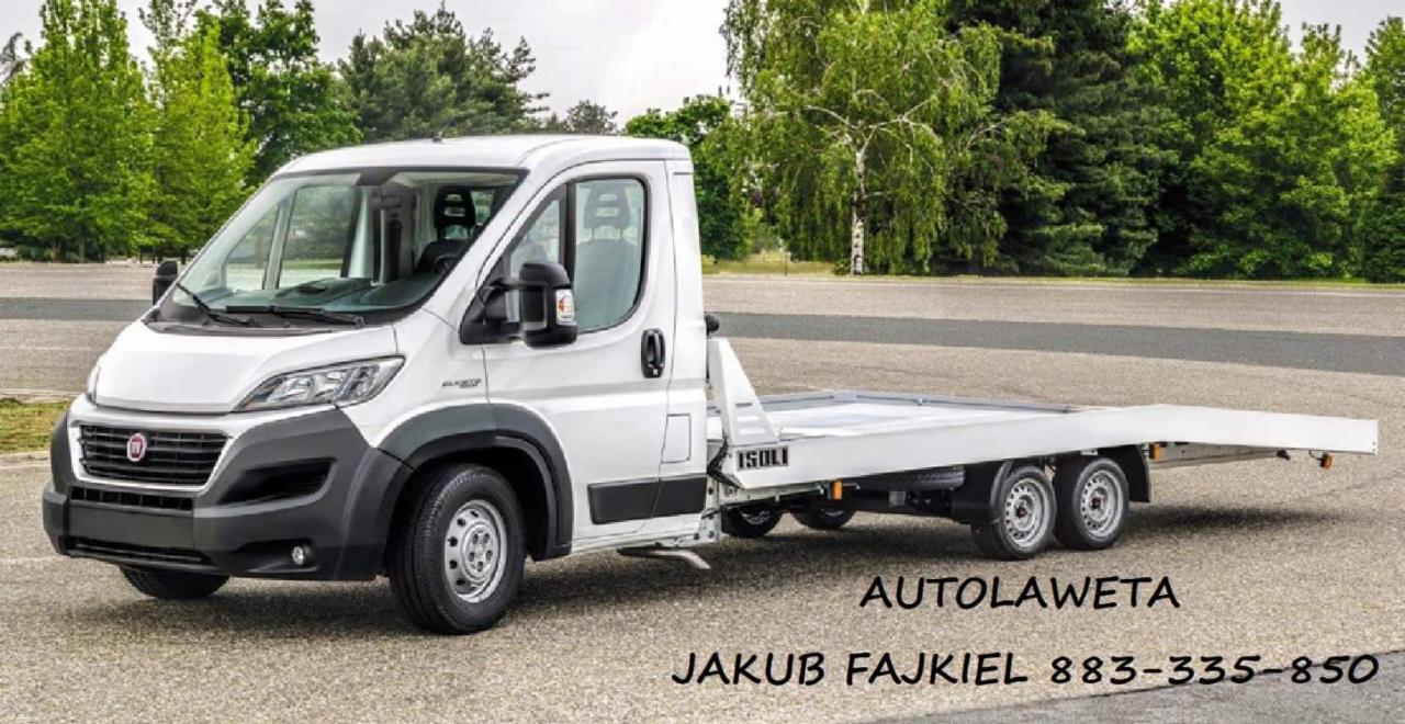 Biała laweta marki Fiat Ducato z platformą załadunkową ISOLI, zaparkowana na asfalcie z zielonymi drzewami w tle, z widocznym numerem telefonu kontaktowego.