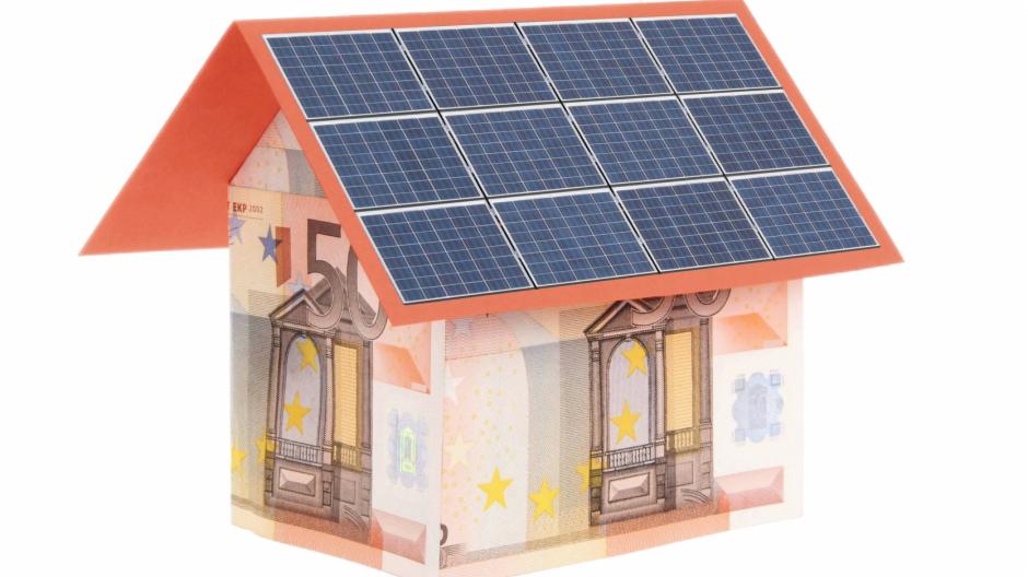 Dom z banknotów 50 euro z dachem z paneli słonecznych, symbolizujący inwestycję w energię odnawialną.