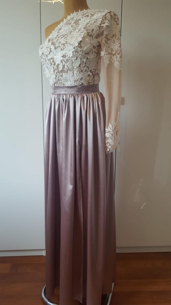 Elegancka, długa suknia wieczorowa w odcieniach pudrowego różu i bieli, z koronkowym, asymetrycznym topem na jedno ramię, prezentowana na manekinie.