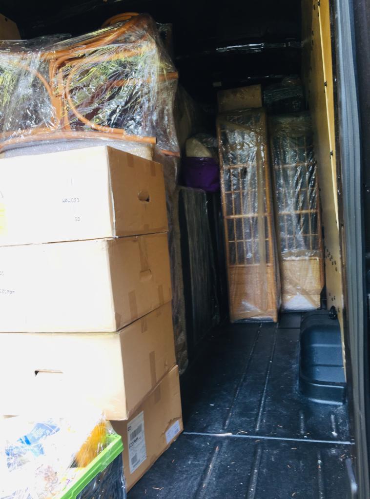 Wnętrze busa załadowane kartonami, krzesłem i elementami wyposażenia wnętrz zabezpieczonymi folią stretch.