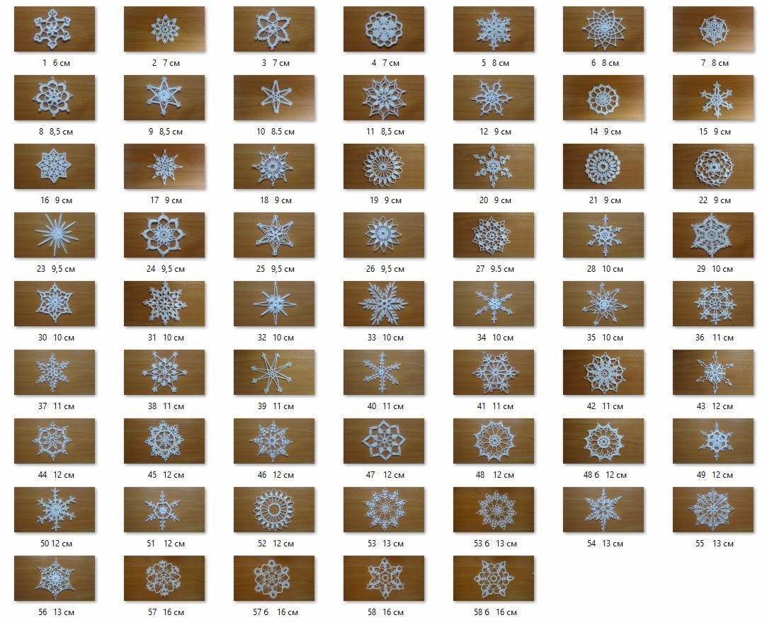 Kolekcja ręcznie robionych, białych, ażurowych śnieżynek o różnych wzorach i rozmiarach (od 6 cm do 16 cm), ułożonych na drewnianym tle.