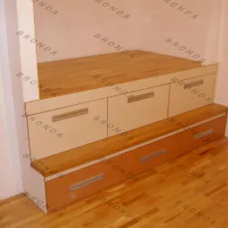 Zabudowa schodowa z szufladami w jasnym drewnie i kremowych frontach, widoczne metalowe uchwyty, podłoga parkietowa, ujęcie z dołu