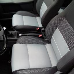 Śliwiński Jarosław - Wnętrze samochodu z dwoma przednimi fotelami po renowacji tapicerki w odcieniach szarości i czerni, widoczne detale wykończenia i faktura materiału.