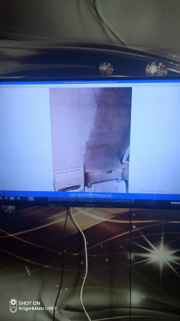 Wnętrze samochodu z widocznym podsufitką i tylnymi siedzeniami, sfotografowane z perspektywy pasażera z tyłu.