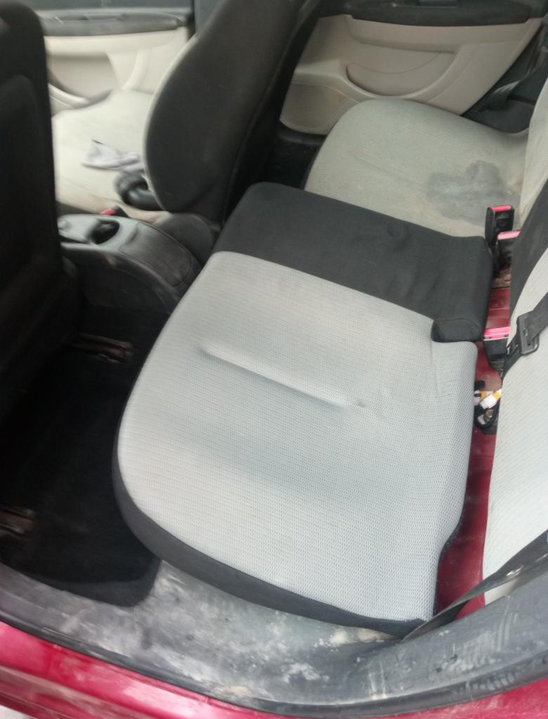 Wnętrze samochodu z widocznymi elementami tapicerki w trakcie demontażu lub montażu, fotele częściowo rozłożone, widoczne ślady użytkowania i zabrudzenia.