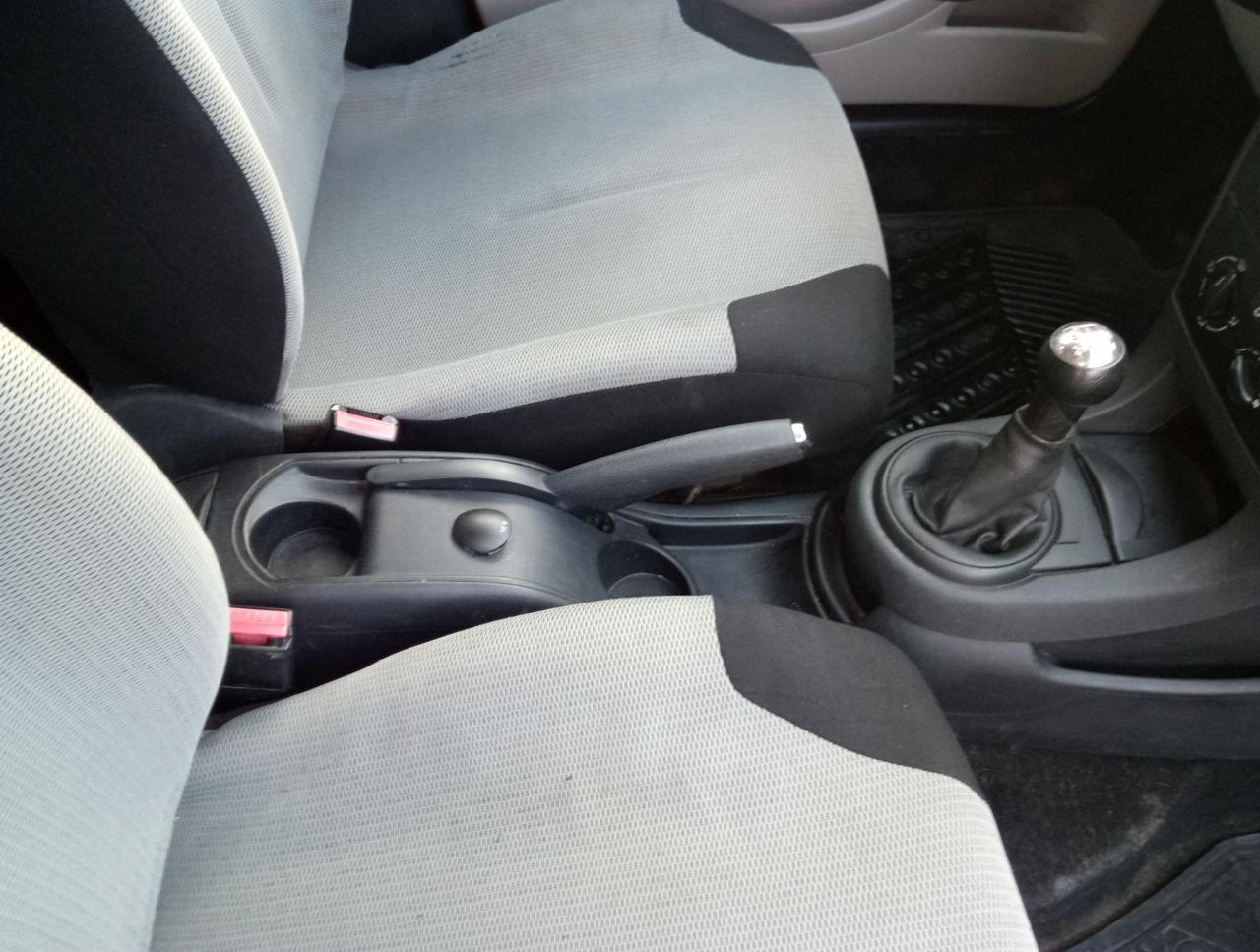 Wnętrze samochodu: szare fotele z czarnymi wstawkami, konsola środkowa z dźwignią zmiany biegów i hamulcem ręcznym, widoczne z bliska.