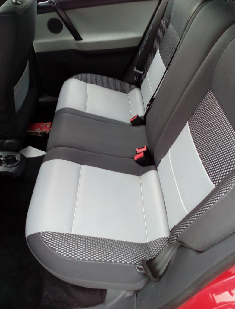 Wnętrze samochodu z tylnymi siedzeniami po renowacji tapicerki, szaro-biała kolorystyka z wzorem w drobną kratkę na obrzeżach.