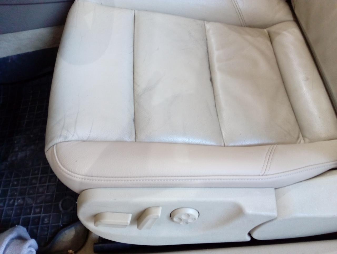 Białe skórzane siedzenie samochodowe z widocznymi śladami użytkowania i regulacją elektryczną.