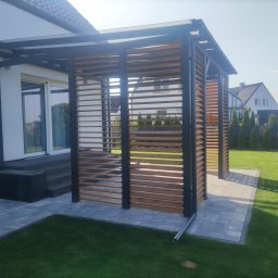 Pan Bruk Patryk Nogal - Nowoczesna pergola z drewnianymi lamelami i metalową konstrukcją, przylegająca do domu, z kostką brukową i trawnikiem. Widok na sąsiedni dom i tuje.