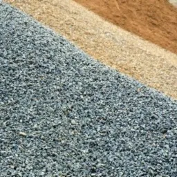 Góra szarego kruszywa w Kartuzach, obok jaśniejszy piasek i brązowa ziemia, ułożone warstwami.