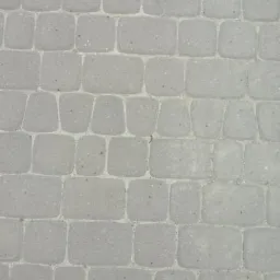 Szara, ułożona kostka brukowa w regularnym wzorze, widok z góry.