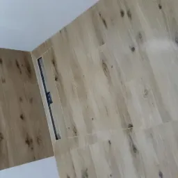 Ukończona łazienka z podłogą i ścianami wyłożonymi płytkami imitującymi drewno oraz zamontowanym odpływem liniowym przy ścianie.