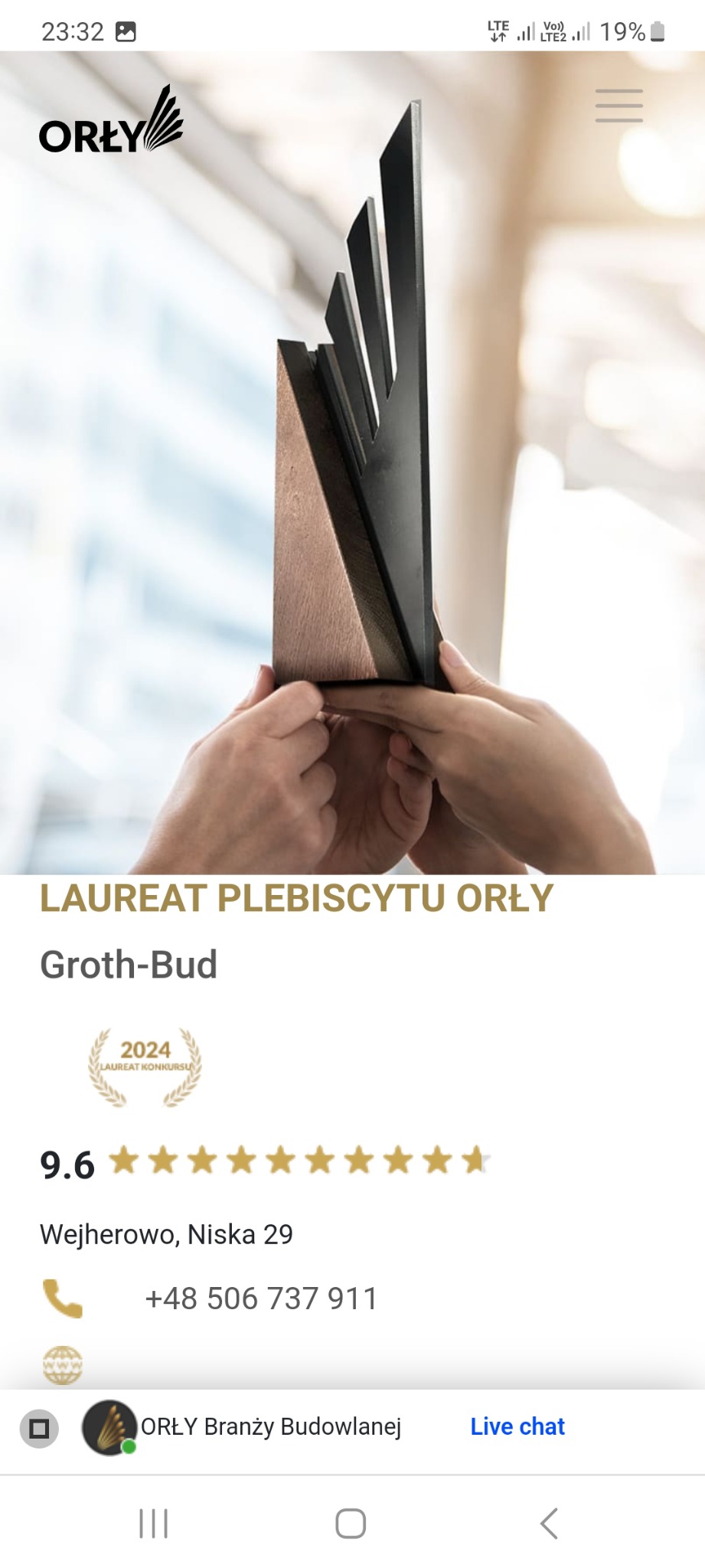 Dłonie trzymające statuetkę konkursu budowlanego Orły, nagroda dla firmy Groth-Bud.