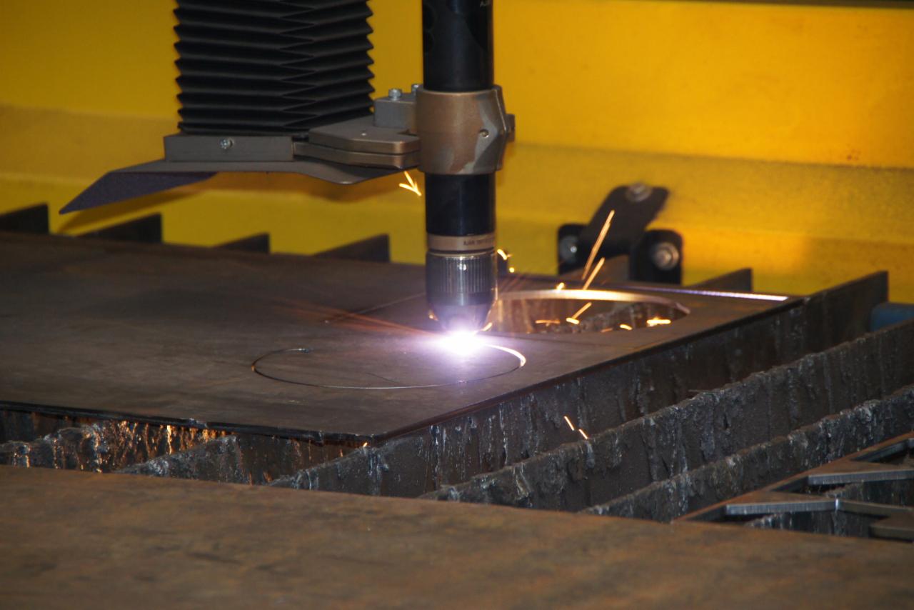 Automatyczne cięcie plazmowe blachy stalowej na maszynie CNC, iskry i opiłki podczas wycinania okręgu.