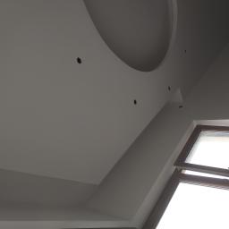 Firma Remontowo Budowlana Tomasz Piechota - Nowoczesny sufit podwieszany z okrągłym wgłębieniem i punktowymi otworami na oświetlenie, jasne ściany i drewniane okno dachowe z otwartym skrzydłem.