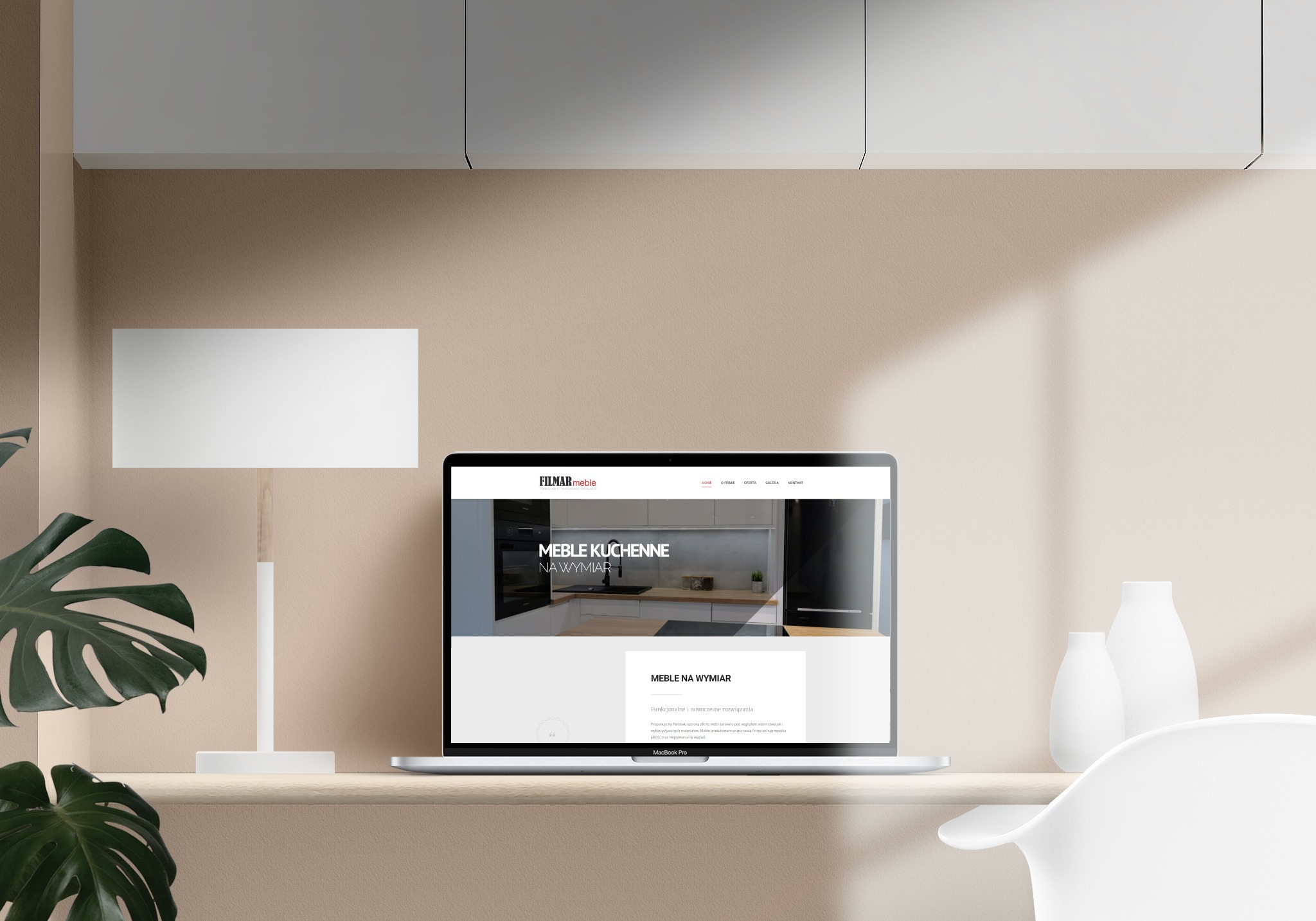 Laptop wyświetla stronę internetową firmy meblarskiej z ofertą mebli kuchennych na wymiar, na biurku obok lampy i dekoracyjnych wazonów, z widocznym cieniem na ścianie.