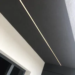 Nowoczesne wykończenie elewacji w Żorach: połączenie ciemnej, strukturalnej powierzchni z liniowym oświetleniem LED i fragmentem okna.