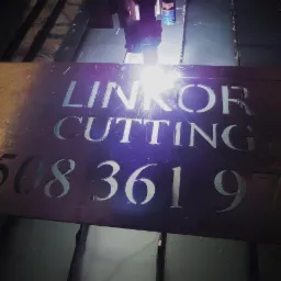 Proces cięcia laserowego blachy z wyciętymi literami 'LINKOR CUTTING' i numerem telefonu 508 361 970. Widoczna wiązka lasera i metalowa powierzchnia.