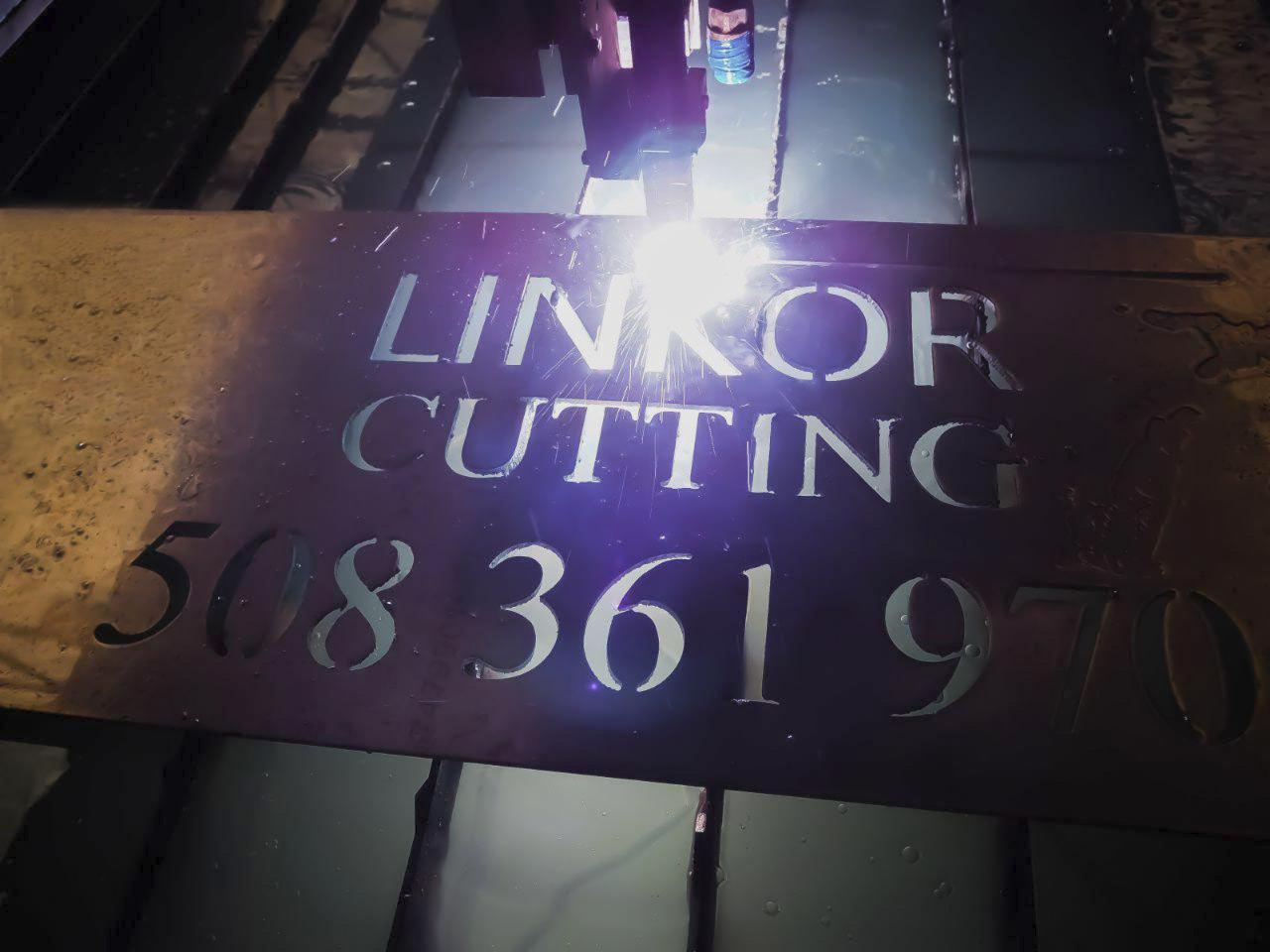 Proces cięcia laserowego blachy z wyciętymi literami 'LINKOR CUTTING' i numerem telefonu 508 361 970. Widoczna wiązka lasera i metalowa powierzchnia.