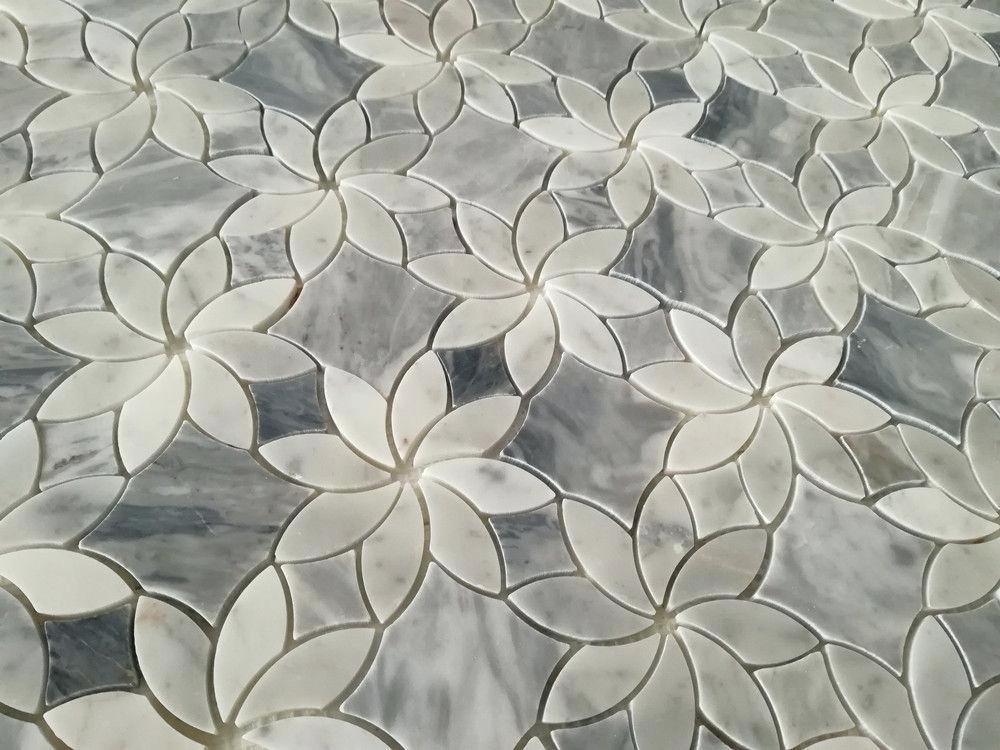 Detal mozaiki podłogowej z białego i szarego marmuru w kształcie kwiatów, ułożonych na gładkiej powierzchni, widoczne naturalne wzory kamienia.