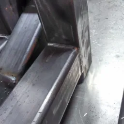 Fragment spawanej konstrukcji bramy wjazdowej z profili stalowych, widoczne spawy i ślady obróbki.