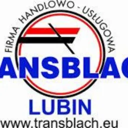 Logo firmy Transblach Lublin z symbolem dachu w czerwono-czarnym okręgu. Nazwa firmy w kolorze niebieskim, poniżej adres strony internetowej.