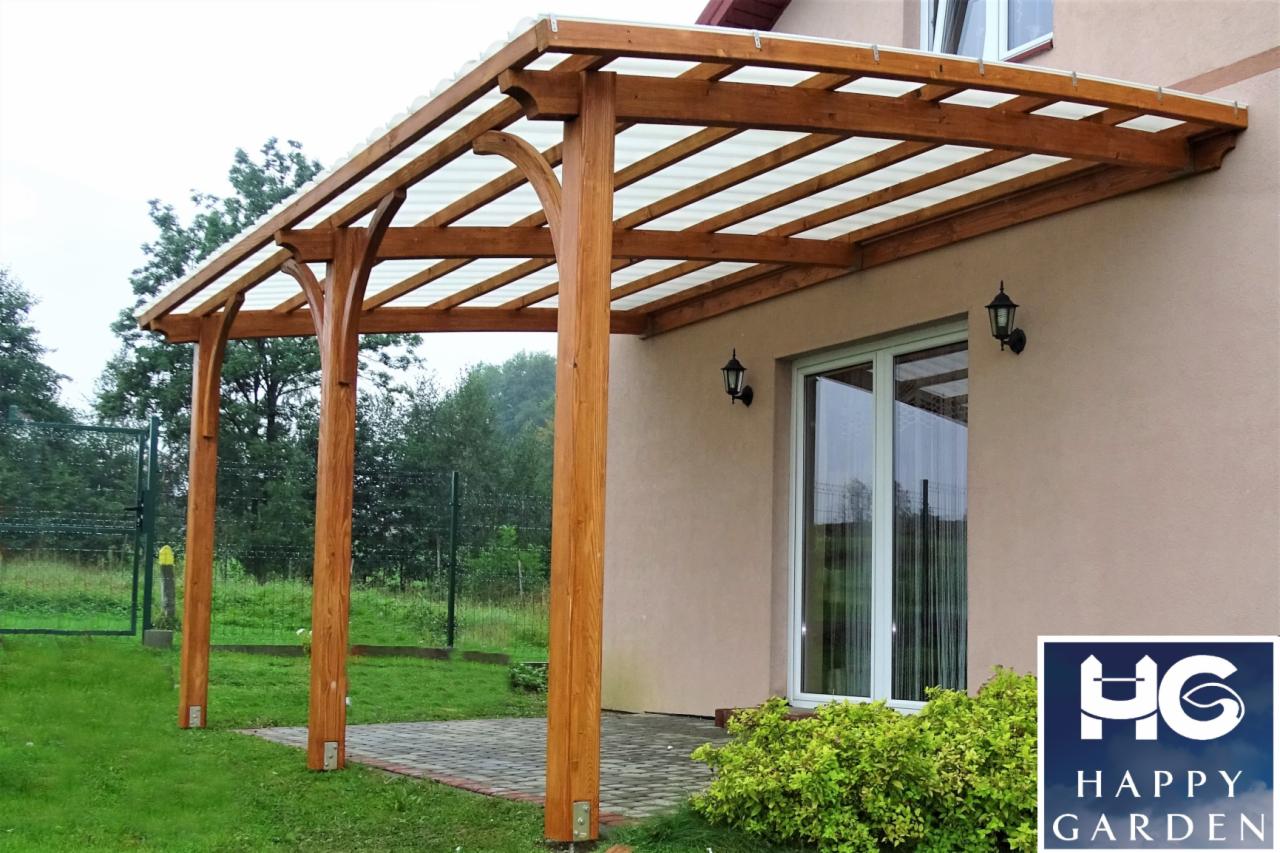 Drewniana konstrukcja z przezroczystym zadaszeniem, wsparta na solidnych, lakierowanych słupach, przylegająca do budynku z oknem i zewnętrznymi lampami. Na pierwszym planie widoczny fragment kostki...