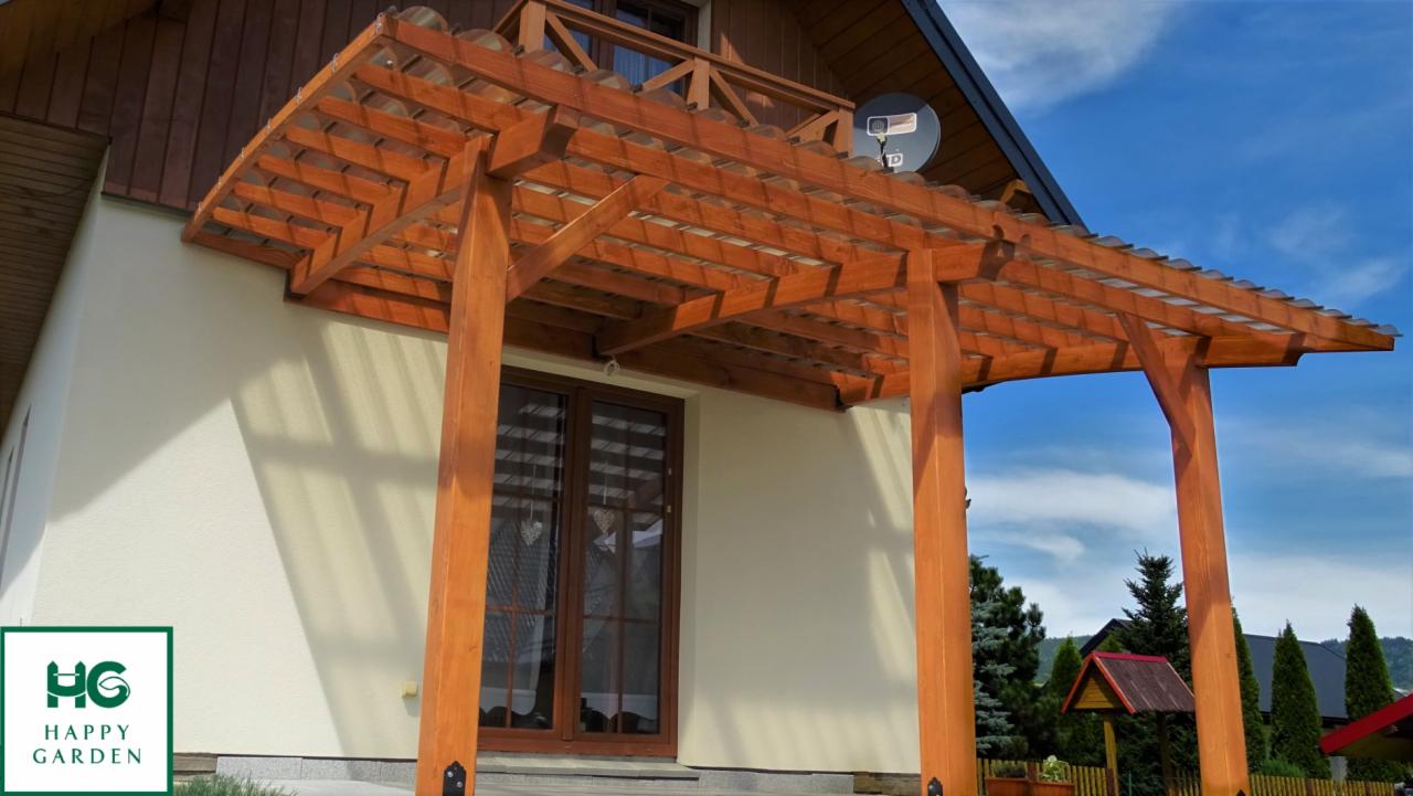 Drewniana konstrukcja z przezroczystym zadaszeniem przy wejściu do budynku, z widocznym logo firmy Happy Garden w lewym dolnym rogu.