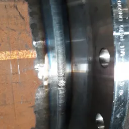 Spoina na rurze stalowej z kołnierzem, widoczne ślady korozji na powierzchni rury