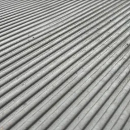 Szara, żebrowana powierzchnia betonowa z widocznymi drobnymi zabrudzeniami i resztkami organicznymi.