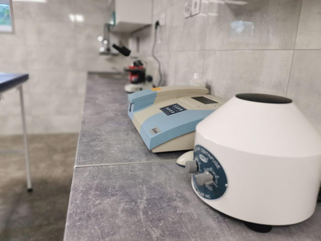 Wyposażenie gabinetu w Biernej: wirówka laboratoryjna, analizator i mikroskop na blacie z szarą fakturą.