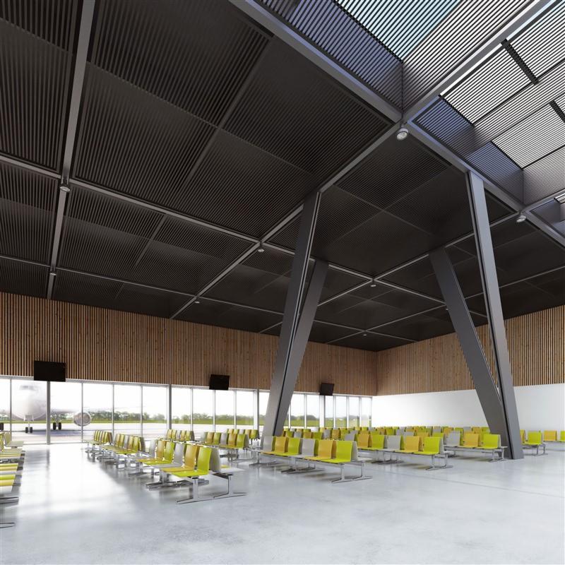 Przestronne wnętrze hali lotniska z rzędami żółto-szarych krzeseł, widok na płytę lotniska przez panoramiczne okna, sufit z metalowych paneli i ukośne, stalowe podpory konstrukcyjne.