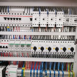 EXEVER SPÓŁKA Z OGRANICZONĄ ODPOWIEDZIALNOŚCIĄ - Rozdzielnia elektryczna z bezpiecznikami, stycznikami i przewodami w kolorach: czarnym, czerwonym i niebieskim. Widoczne elementy marki ABB i Eaton.