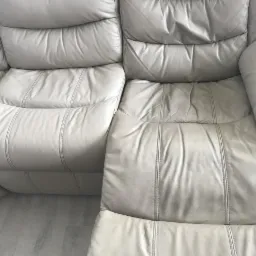 Fragment jasnej, skórzanej kanapy z widocznymi śladami użytkowania przed czyszczeniem w Sulejówku. Widoczne zagniecenia i delikatne zabrudzenia na siedzisku.