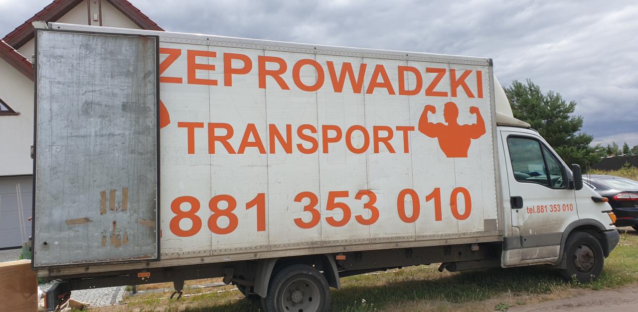 Biała furgonetka z otwartymi tylnymi drzwiami, pomalowana na biało z pomarańczowym napisem 'ZEPROWADZKI TRANSPORT' i numerem telefonu, zaparkowana na trawniku przed domem.