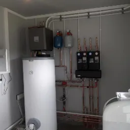 Kompletna instalacja grzewcza NIBE w kotłowni: zbiornik buforowy, zasobnik ciepłej wody, moduł wewnętrzny, rozdzielacze i orurowanie z miedzi.
