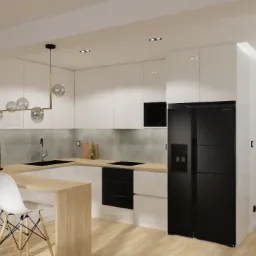 Nowoczesna kuchnia z białymi szafkami, czarnym sprzętem AGD i drewnianym blatem, oświetlona wiszącą lampą z kulistymi kloszami, widziana z perspektywy salonu.