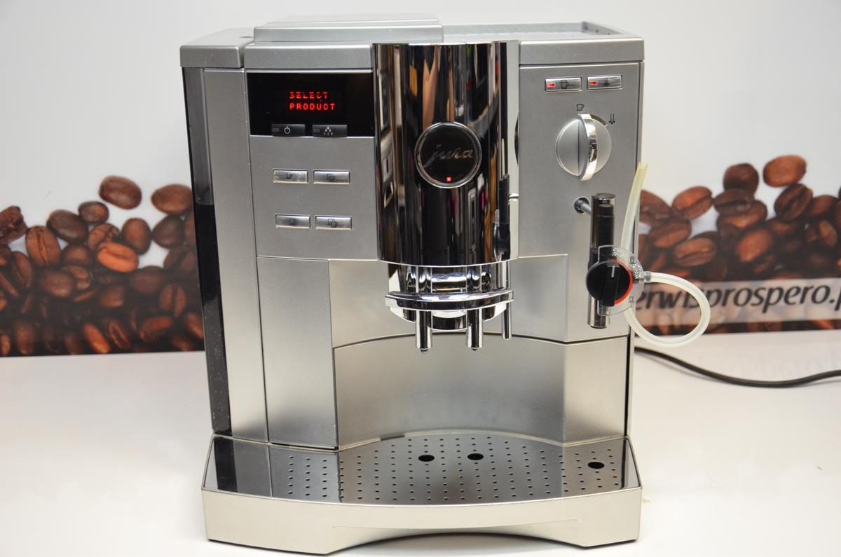 Srebrny ekspres do kawy marki Jura z wyświetlaczem i chromowanymi elementami, widoczny na tle z motywem ziaren kawy.