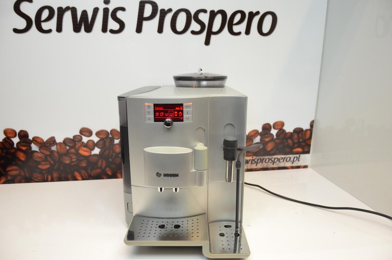Srebrny ekspres do kawy marki Bosch z wyświetlaczem, na tle reklamy Serwis Prospero i ziaren kawy.