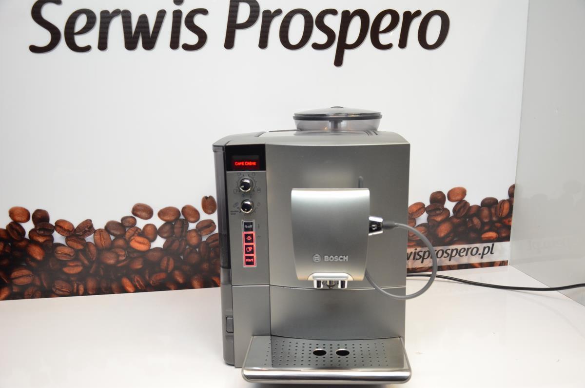 Szary ekspres do kawy Bosch sfotografowany w Żelazkowie na tle reklamy Serwis Prospero z motywem ziaren kawy.