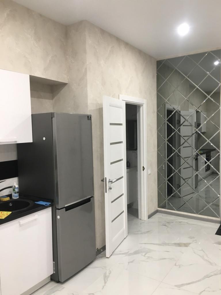 Wykończona kuchnia w Warszawie z dekoracyjną ścianą z lustrzanych płytek w romby, marmurowa podłoga i ściany w odcieniach beżu.