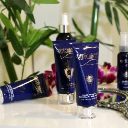 Kompozycja kosmetyków marki Repechage: tubki z maską peelingującą, butelki z serum, dekoracyjne lustro i bambus na białym blacie.