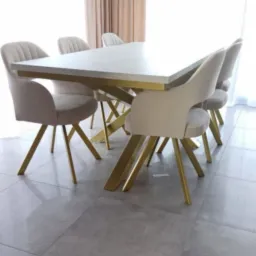 Jasny stół z blatem imitującym kamień i złotymi nogami w kształcie litery X, otoczony krzesłami z beżową tapicerką i złotymi nogami, pod nowoczesną lampą.