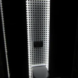 Nowoczesna toaleta podwieszana, podświetlona mozaiką w odcieniach bieli i czerni, z ciemnymi ścianami i podłogą z tej samej mozaiki.