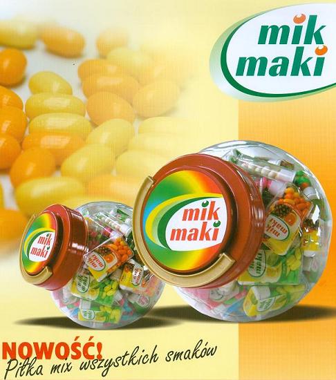 Dwa przezroczyste słoiki w kształcie kuli wypełnione drażetkami owocowymi MIK MAKI, z logo firmy na wieczku, na tle z rozmytymi drażetkami i napisem 'Nowość! Piłka mix wszystkich smaków'.