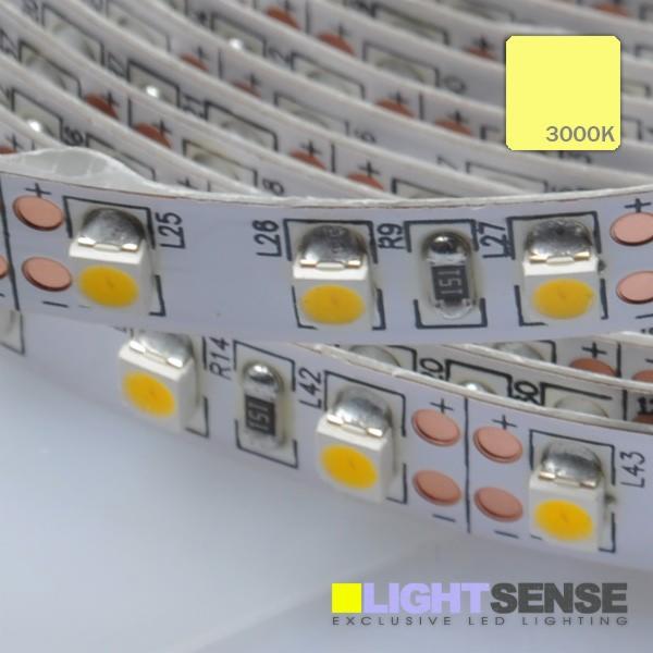 Zbliżenie na zwiniętą taśmę LED SMD3528, o barwie światła 3000K, z widocznymi diodami, rezystorami i ścieżkami zasilającymi na białym podłożu.