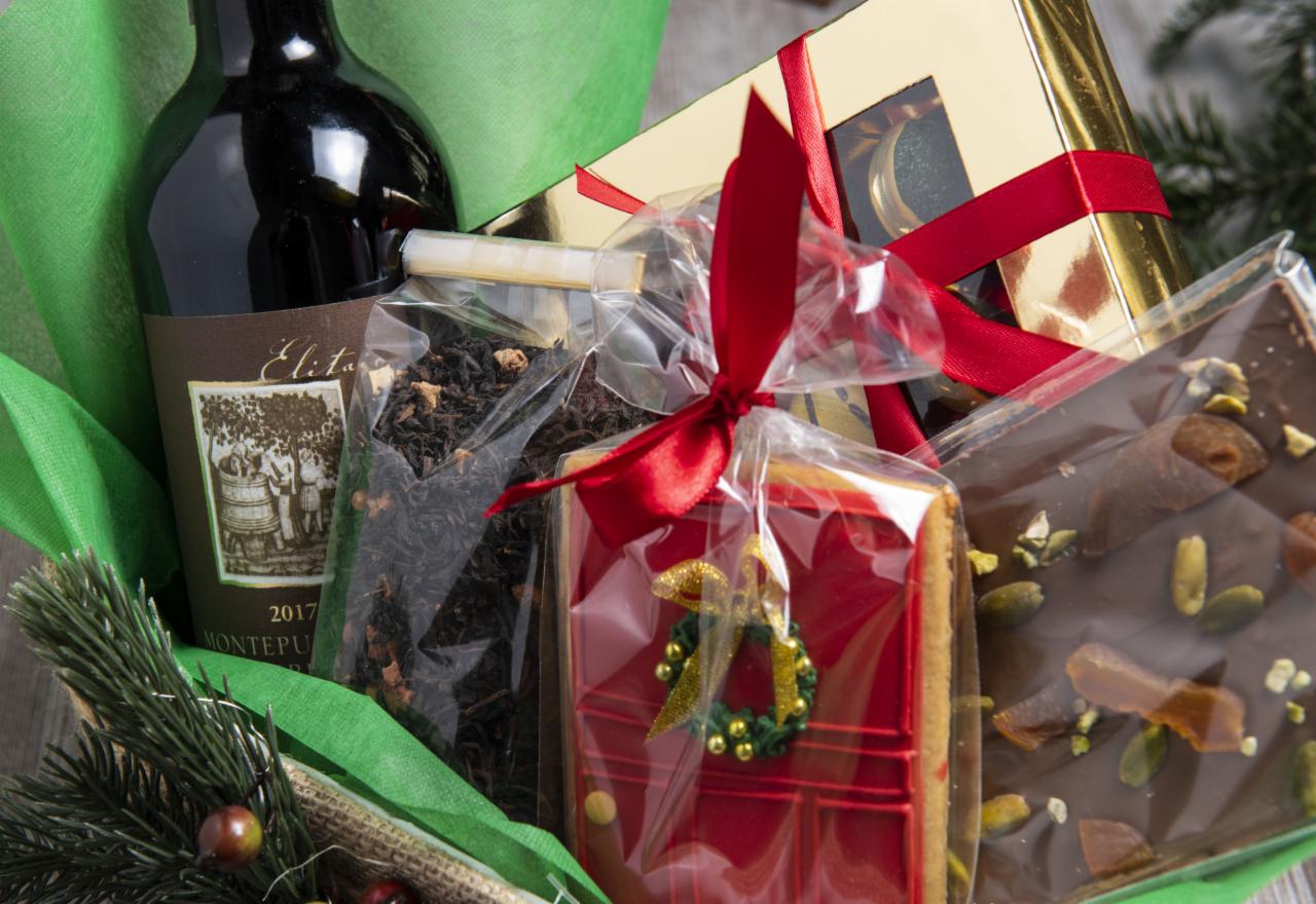 Zestaw upominkowy: butelka wina Montepulciano 2017, herbata liściasta, czekolada z pistacjami i morelami, piernik w kształcie drzwi z lukrowanym wieńcem, zapakowane w złoty kartonik z czerwoną...