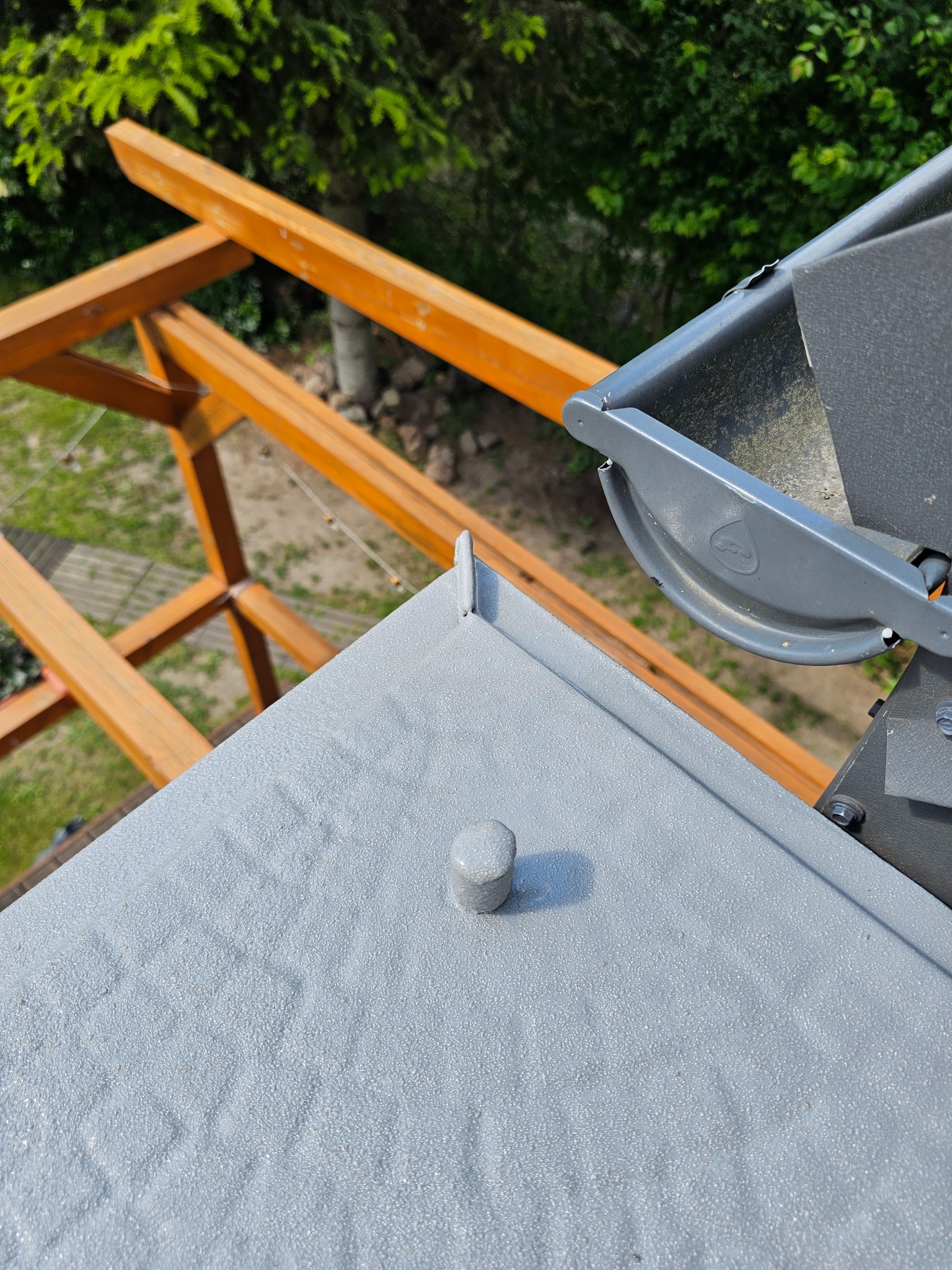 Szara, chropowata posadzka żywiczna z widocznym odpływem i drewnianą konstrukcją w tle, wykonana w Gulin. Detal z bliska.