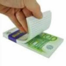 Stos banknotów euro z odklejaną białą kartką na wierzchu, sugerującą ukryte koszty lub warunki finansowe. Ujęcie z góry, lekki kąt.