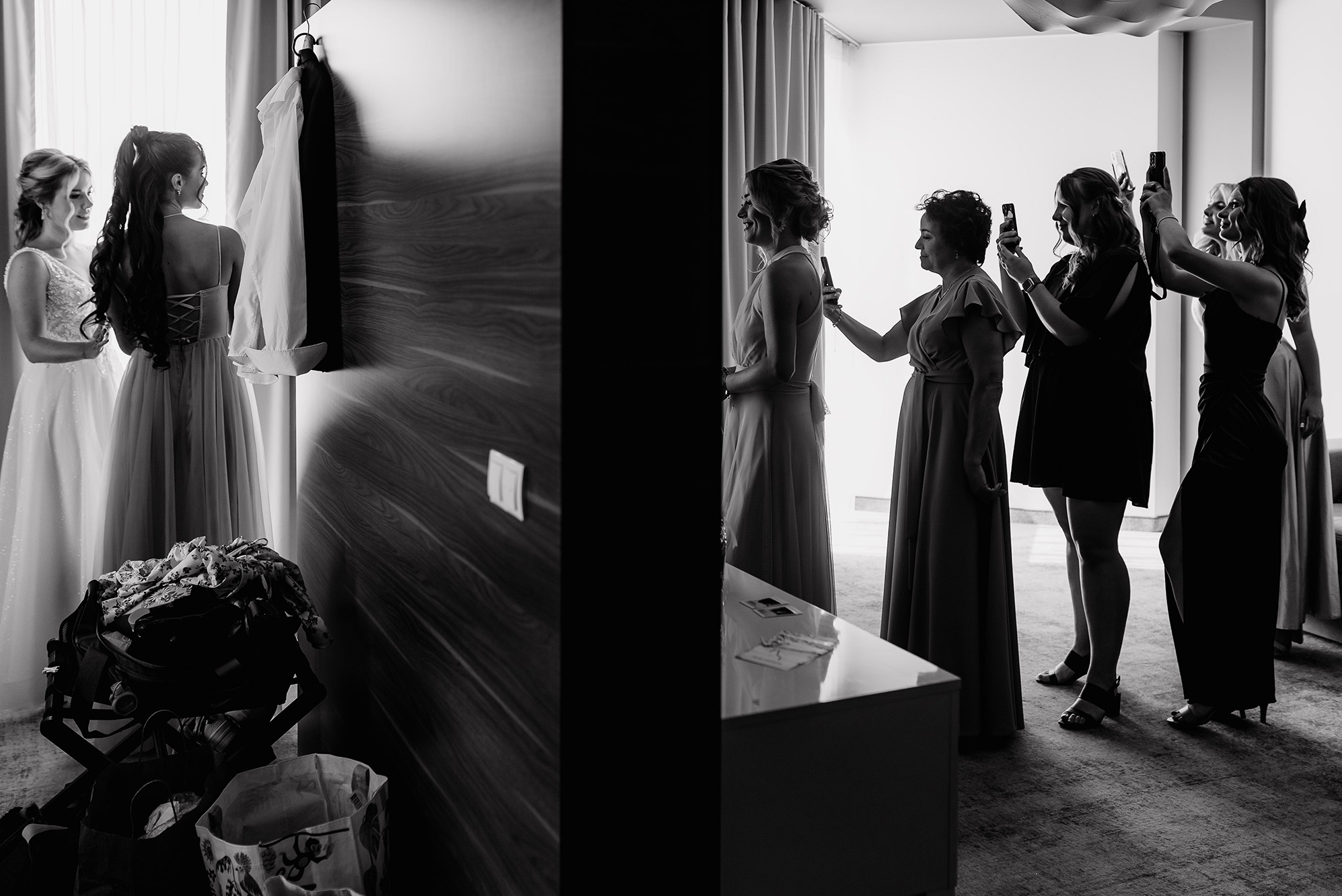 Czarno-białe zdjęcie z przygotowań ślubnych: panna młoda z druhnami w pokoju hotelowym, ujęcia z różnych perspektyw, emocje i detale.